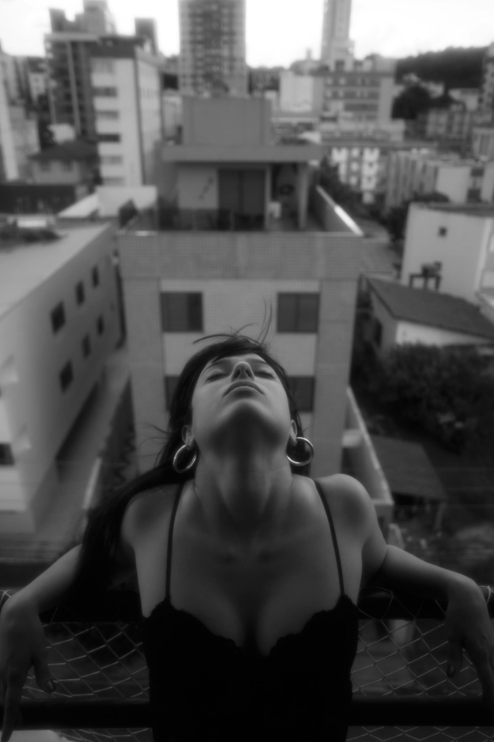 Black and white portrait of a woman with eyes closed in an urban Brazilian setting. Captivating and artistic.